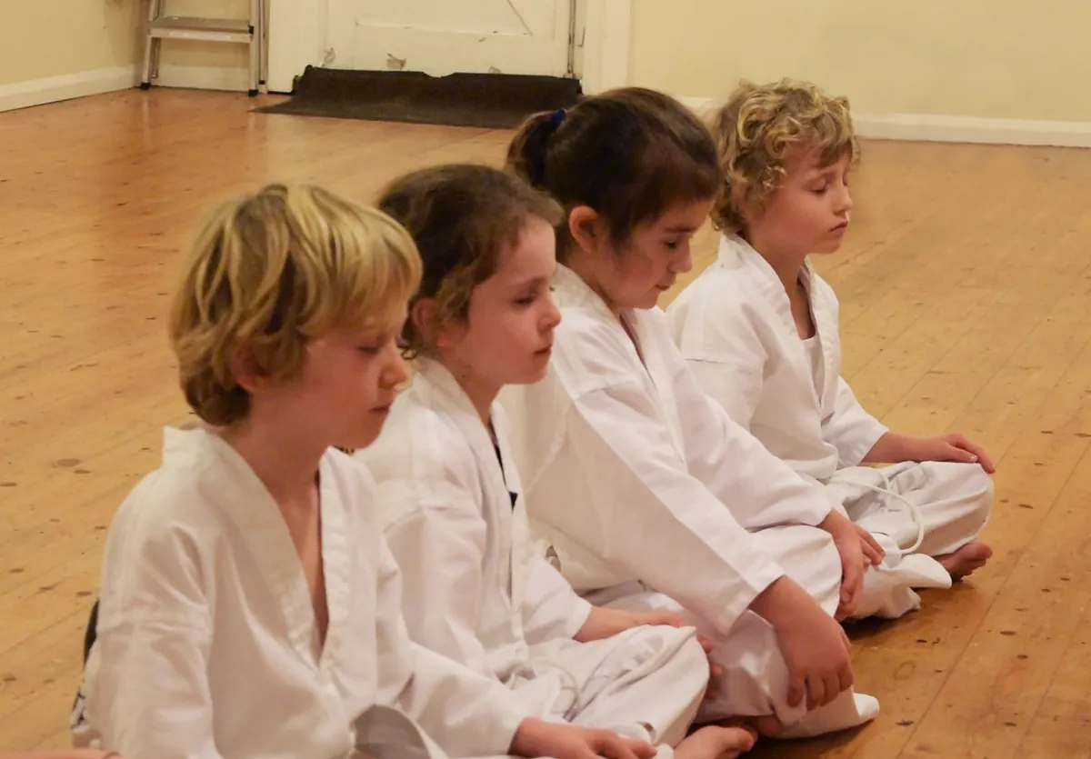 Students sitting in a line on the training hall floor, listening